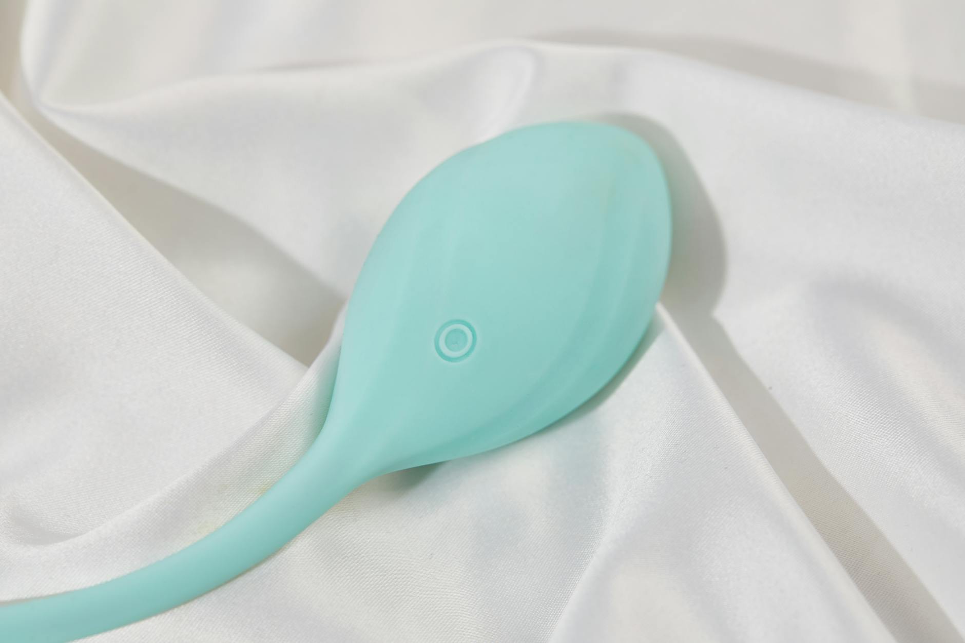 A teal lemon vibrator on white silk fabric, representing modern clitoral suction technology