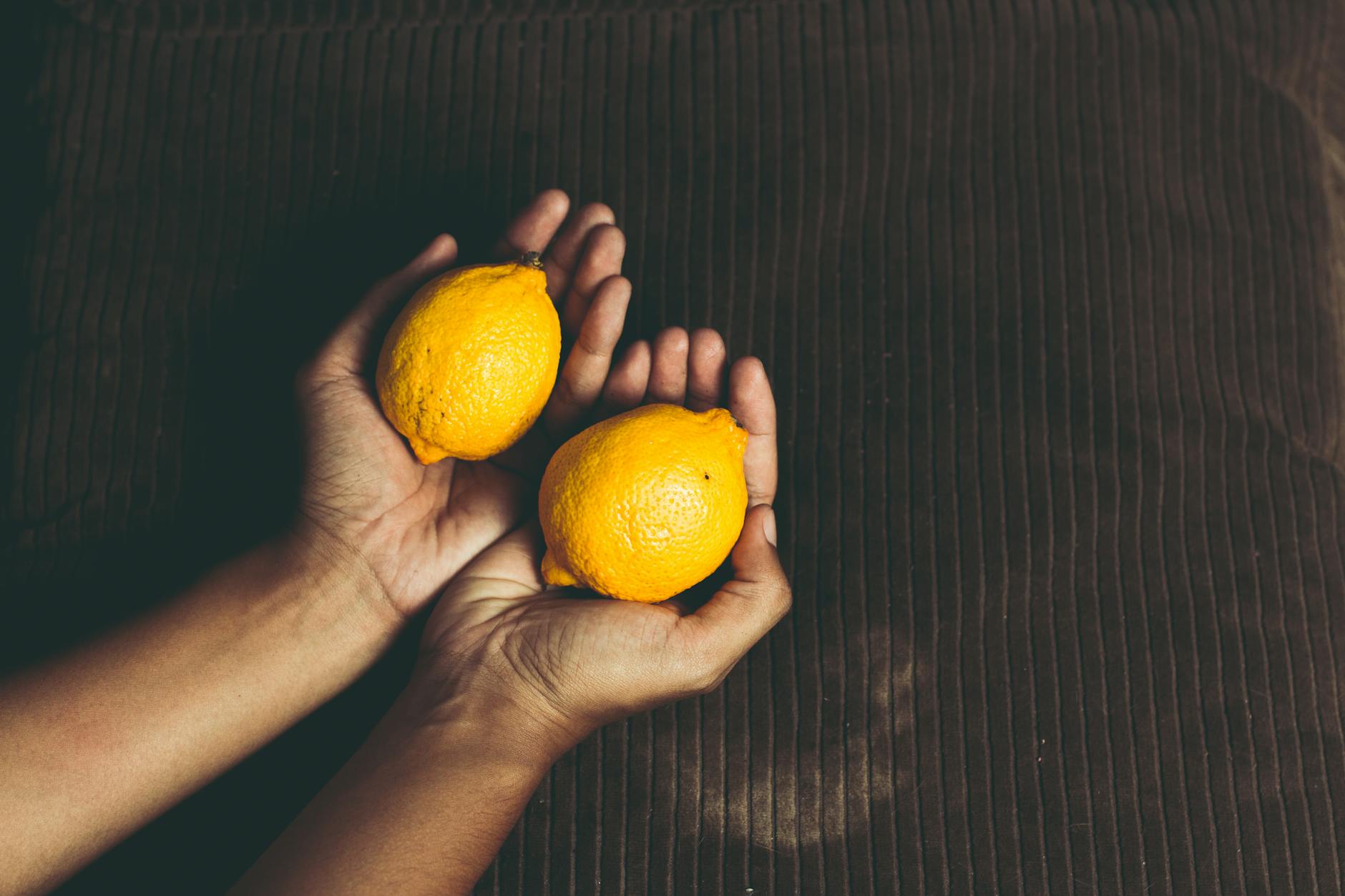 Two fresh lemons held in cupped hands, symbolizing the gentle, intentional approach to pleasure during menopause