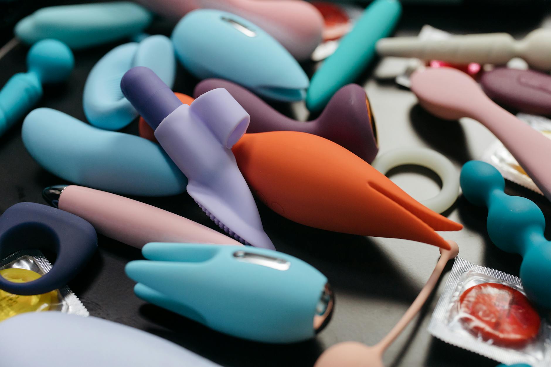 Woman holding blue and pink vibrators, showing comfort and confidence with intimate wellness tools.