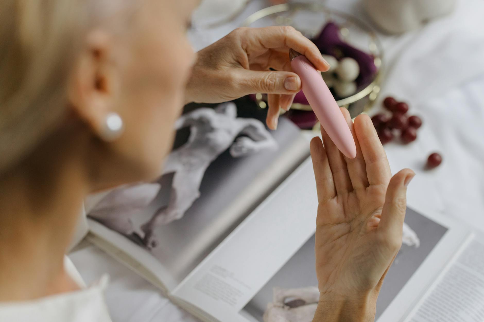 Close-up of a pink clitoral vibrator held in hand, emphasizing intimate self-care and sexual wellness.