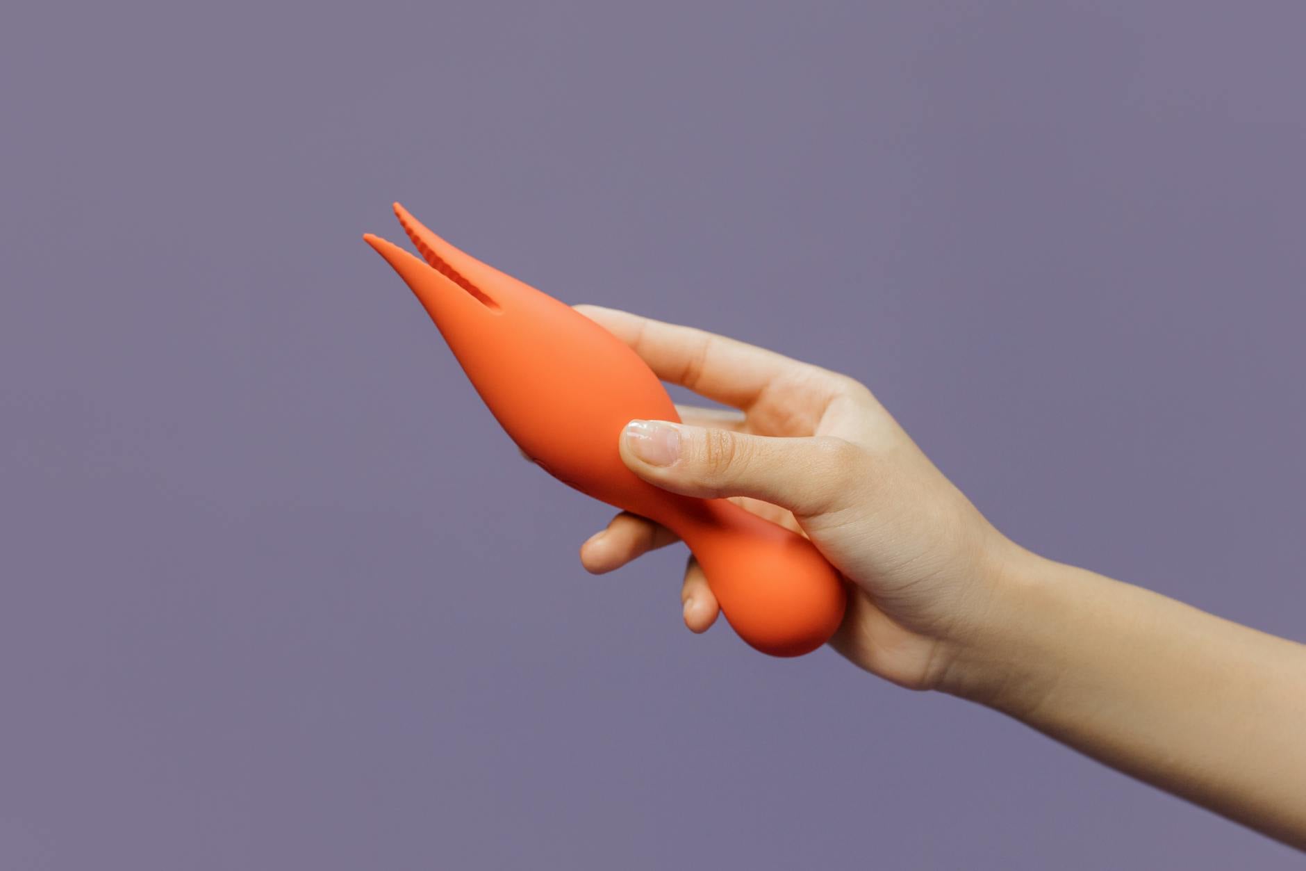 Mano sosteniendo un vibrador de limón contra un fondo púrpura minimalista, mostrando sensualidad moderna