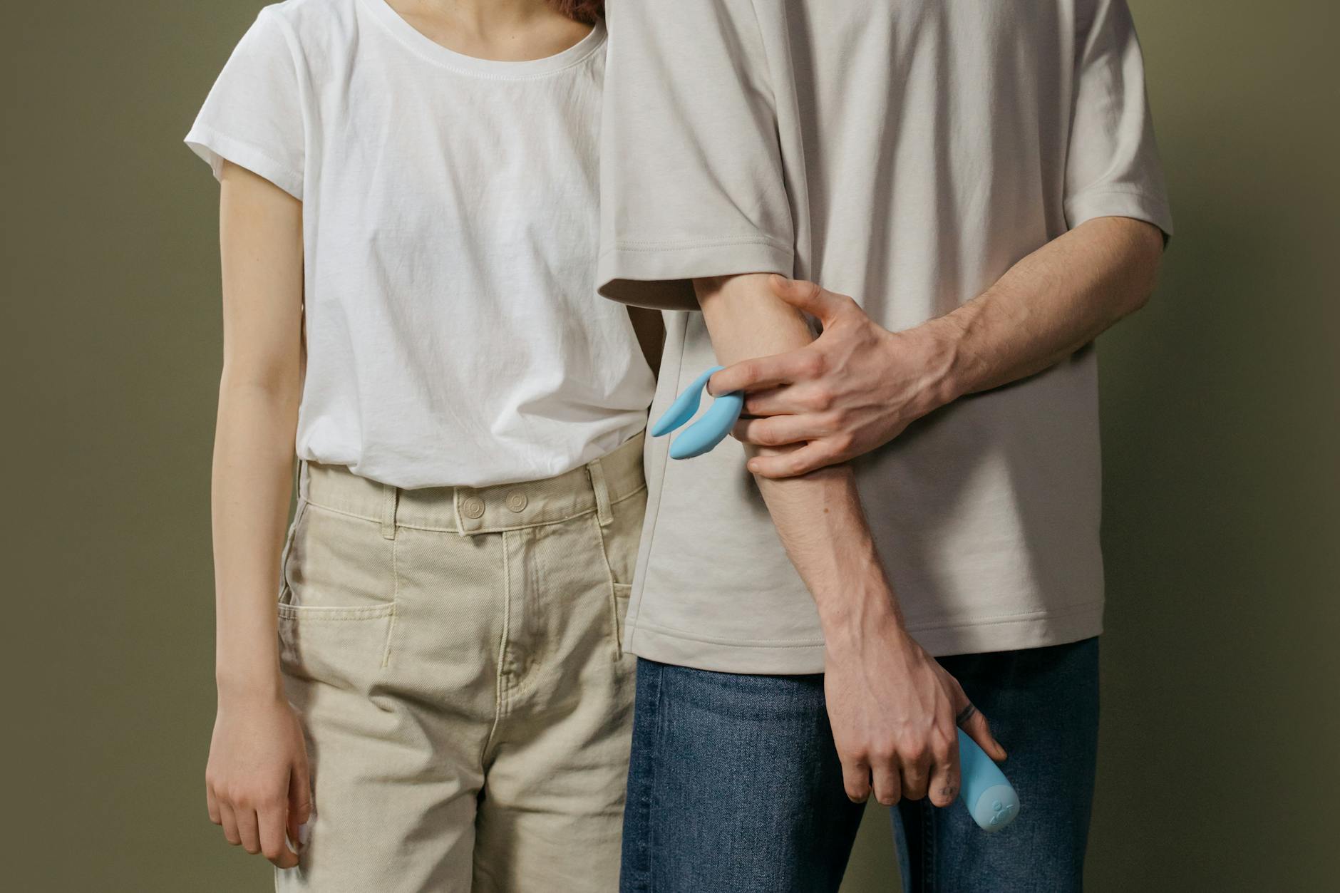 A couple standing close together, holding a blue vibrator, representing modern couples exploring intimacy together