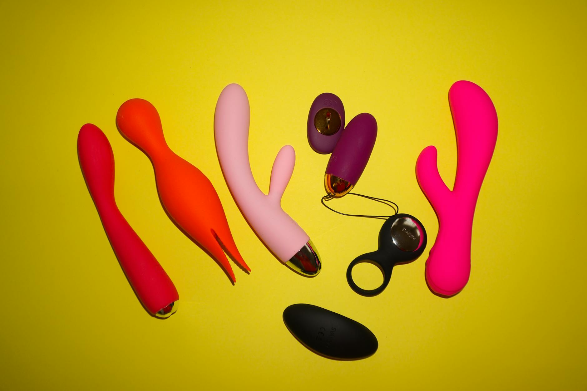 Colorful lemon vibrators and adult toys arranged on a bright yellow surface